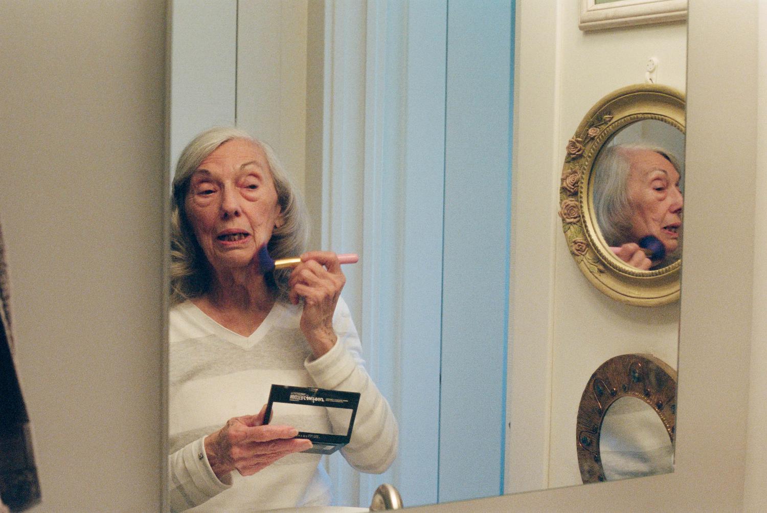 photo of a woman applying make up at a mirror